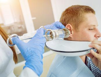 Врач-отоларинголог проводит осмотр взрослого пациента на дому в Москве с использованием медицинских инструментов