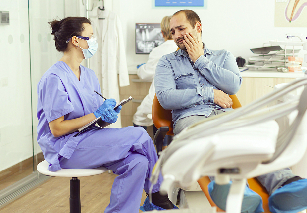 Отоларинголог осматривает пациента во время экстренного приёма в круглосуточной клинике