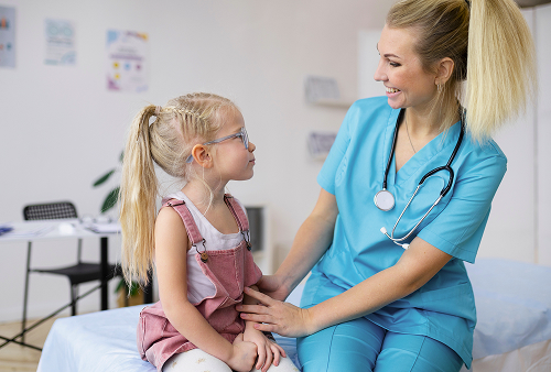 Детский гастроэнтеролог осматривает ребёнка в кабинете клиники, объясняя результаты обследования родителям.